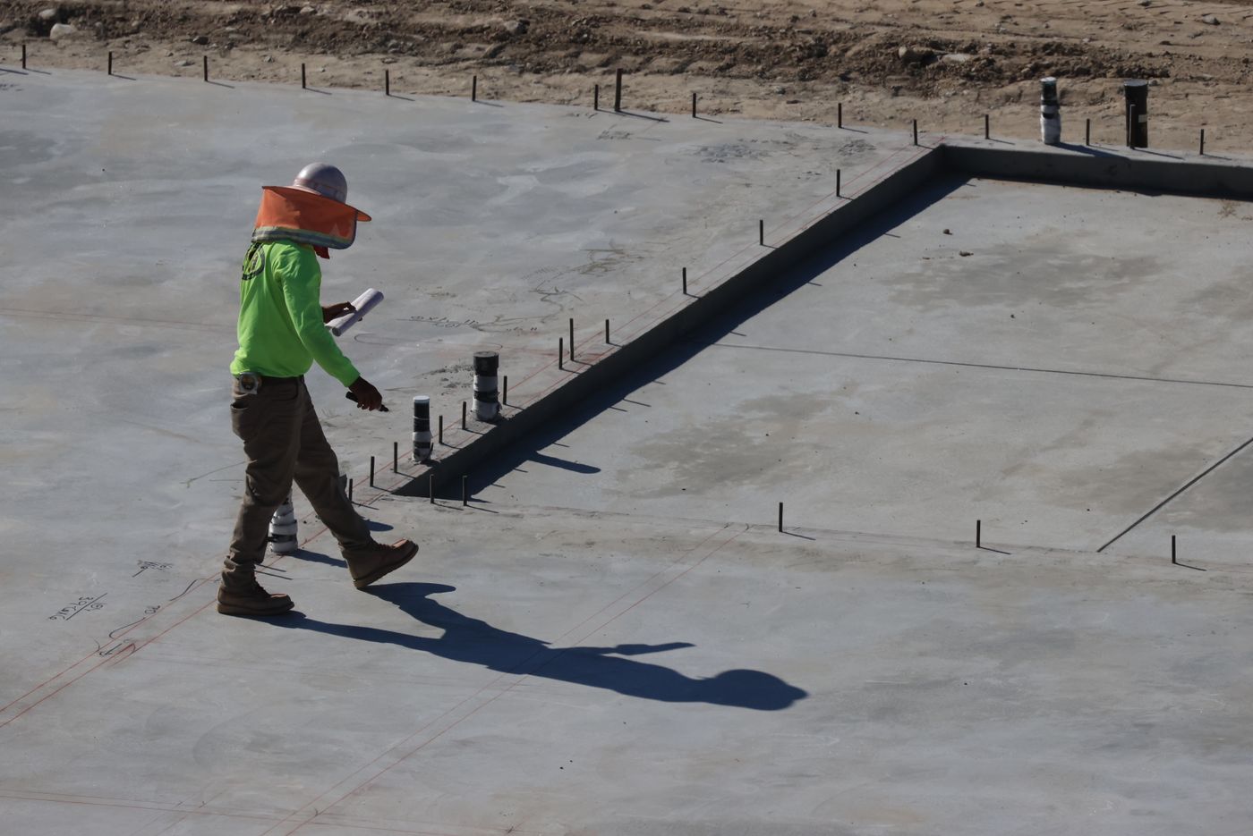A construction worker inspecting a concrete ground slab
