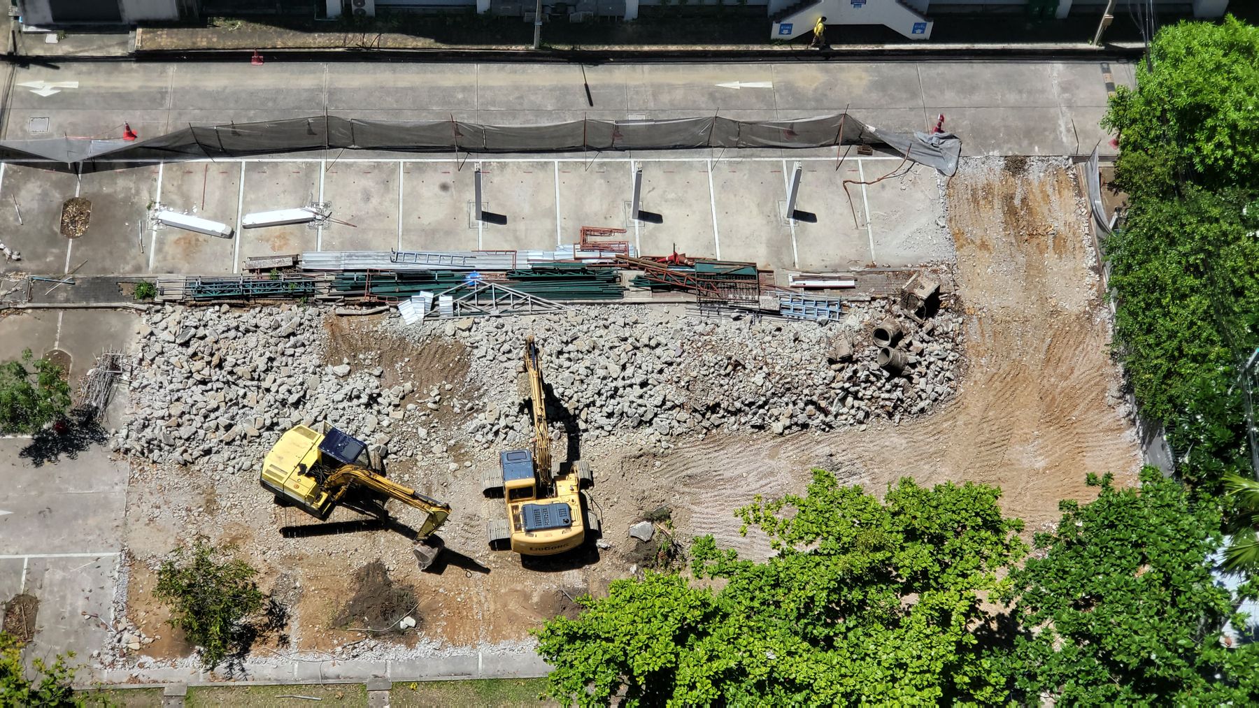 Two yellow excavators working on an urban earthworks site