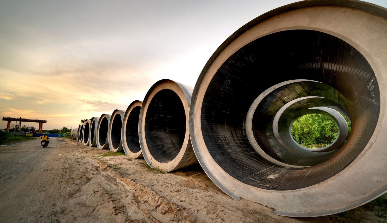 Large concrete pipe sections arranged in a row beside a site access track