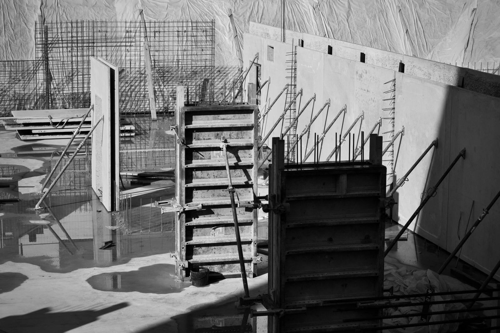 Black-and-white view of concrete wall panels, steel reinforcement and supporting formwork