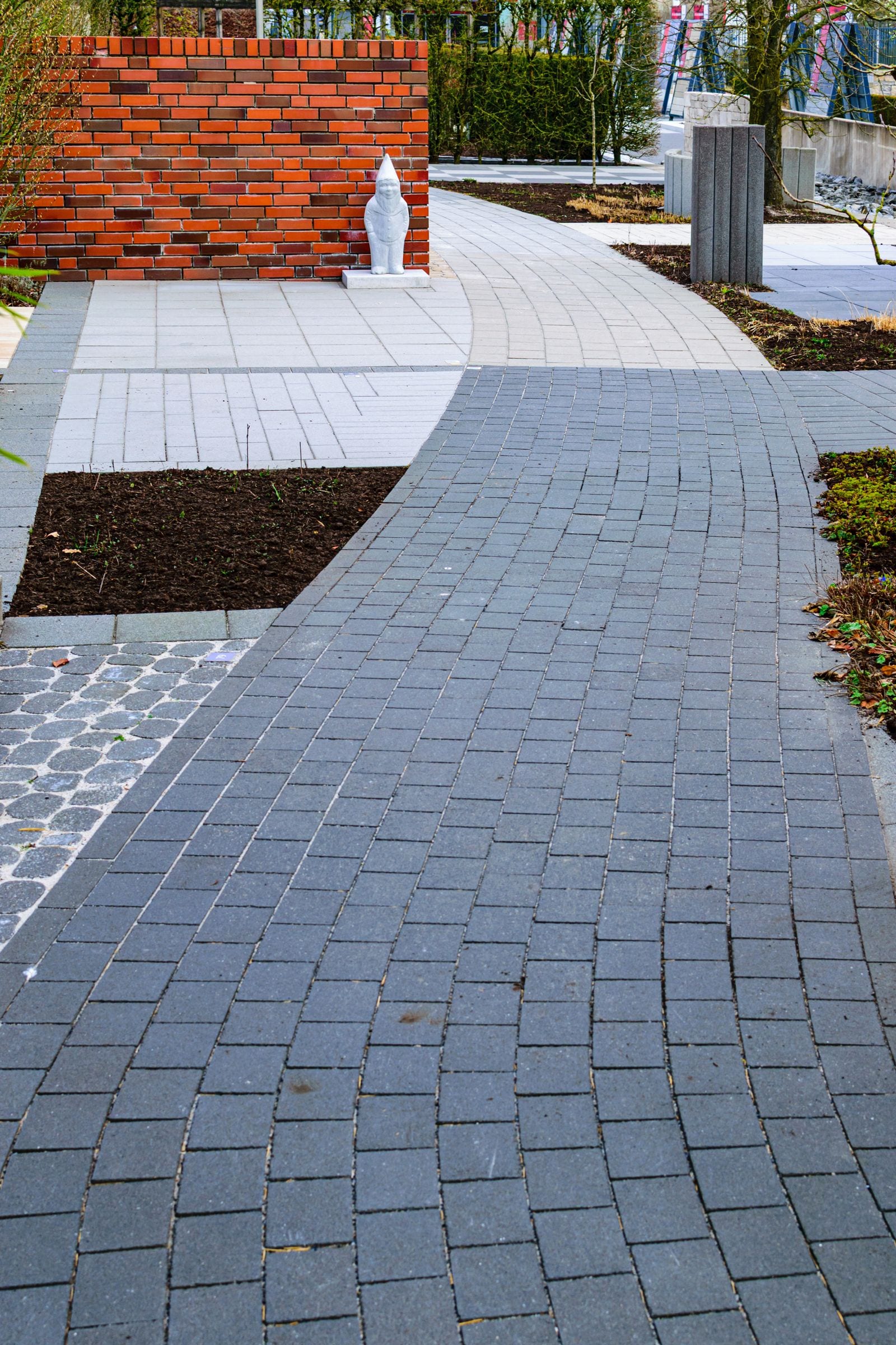 Curved paving through planted borders with low brick and concrete landscape features