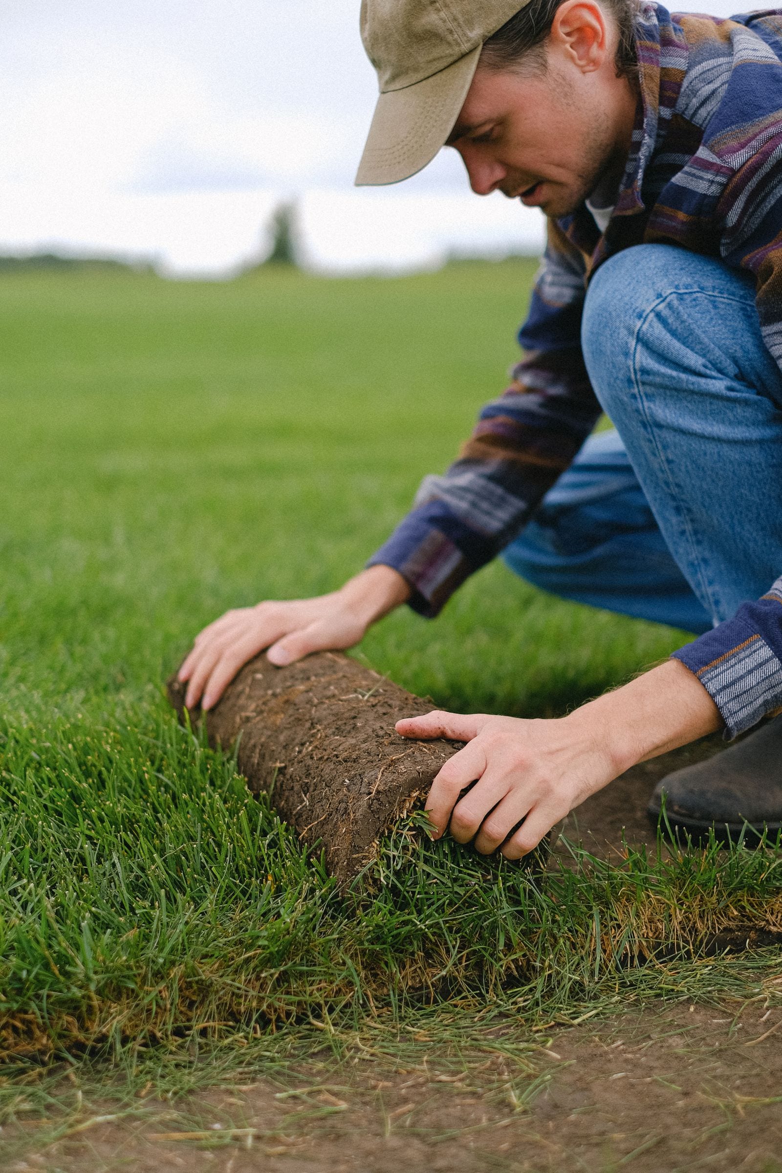 A landscaper unrolling fresh turf by hand