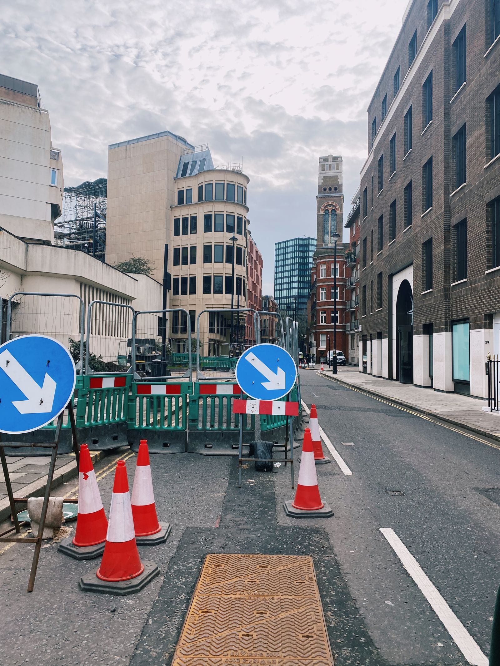 Temporary barriers, traffic cones and keep-right signs around roadworks on a London street
