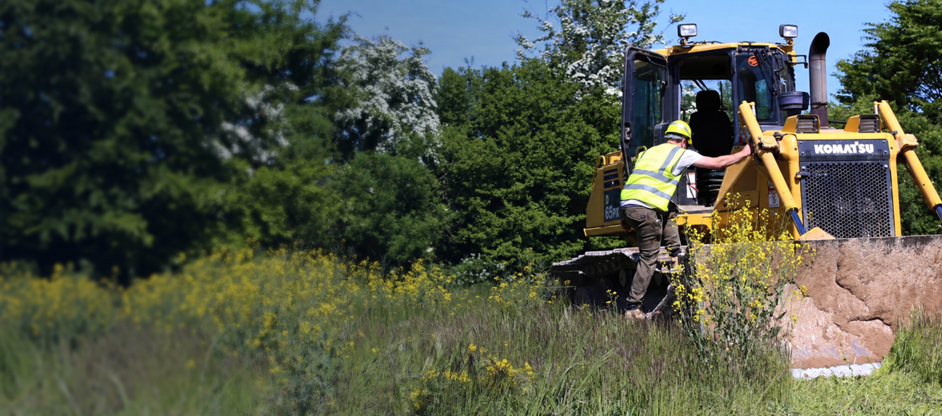 An operative approaching a yellow bulldozer during site preparation